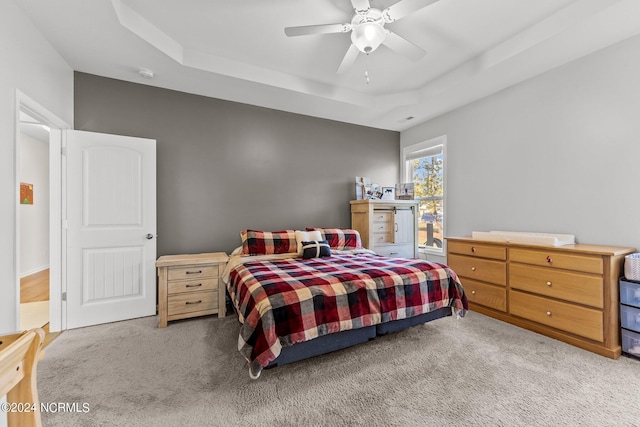 carpeted bedroom featuring a raised ceiling and ceiling fan