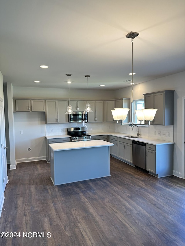 kitchen featuring stainless steel appliances, dark hardwood / wood-style flooring, sink, pendant lighting, and a kitchen island