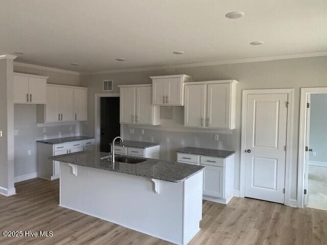 kitchen featuring sink, a center island with sink, and white cabinets