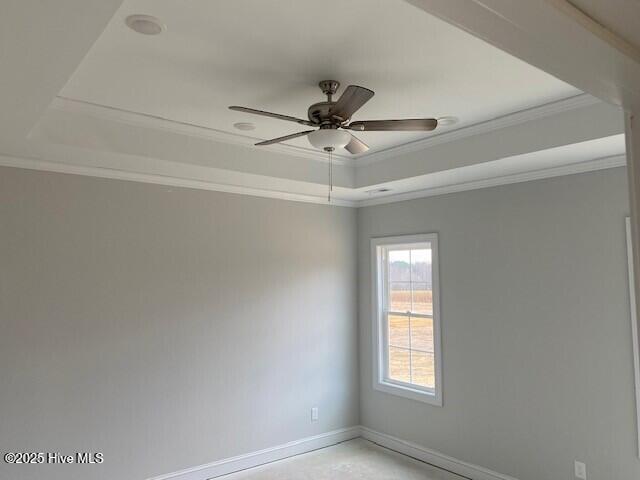 empty room featuring ornamental molding, a raised ceiling, and ceiling fan