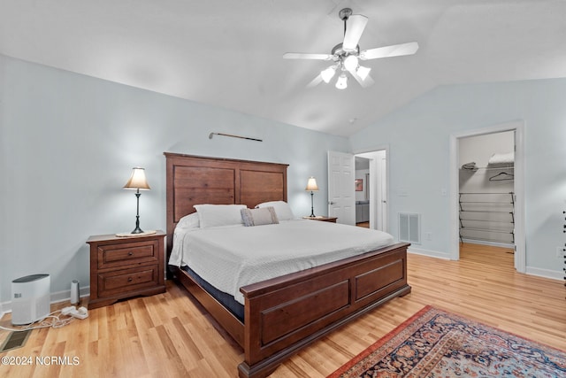 bedroom with ceiling fan, a spacious closet, vaulted ceiling, light hardwood / wood-style floors, and a closet