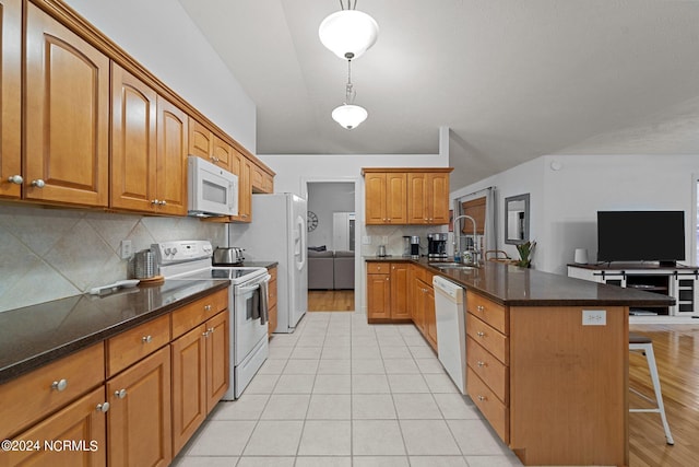 kitchen featuring hanging light fixtures, a breakfast bar, light hardwood / wood-style flooring, sink, and white appliances