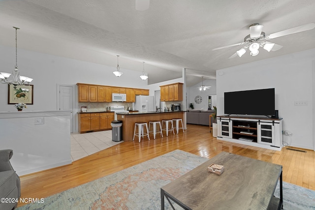 living room with vaulted ceiling, a textured ceiling, light hardwood / wood-style flooring, and ceiling fan with notable chandelier