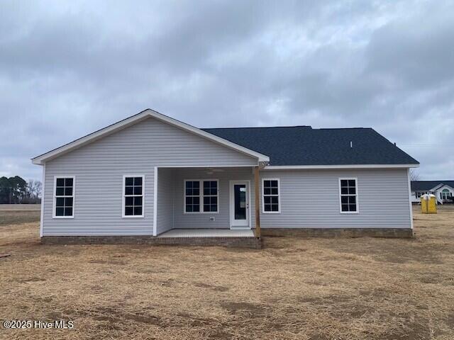 back of property with a lawn and a patio