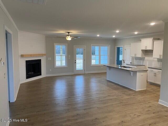 kitchen featuring a kitchen island with sink, sink, white cabinetry, and a kitchen bar