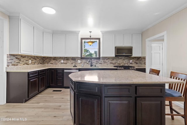 kitchen with a breakfast bar area, light hardwood / wood-style flooring, decorative light fixtures, white cabinetry, and stainless steel appliances