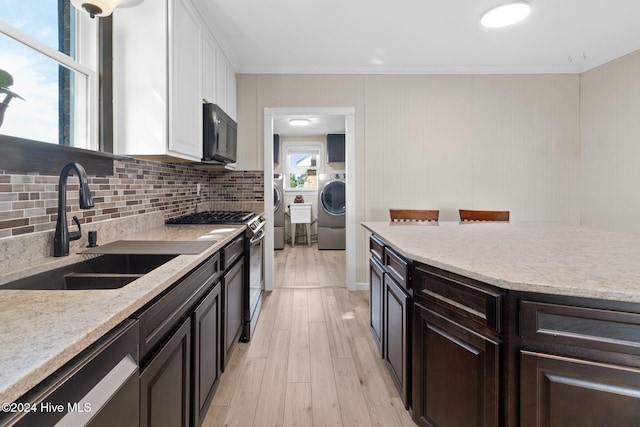 kitchen featuring plenty of natural light, light hardwood / wood-style floors, washer / dryer, and appliances with stainless steel finishes