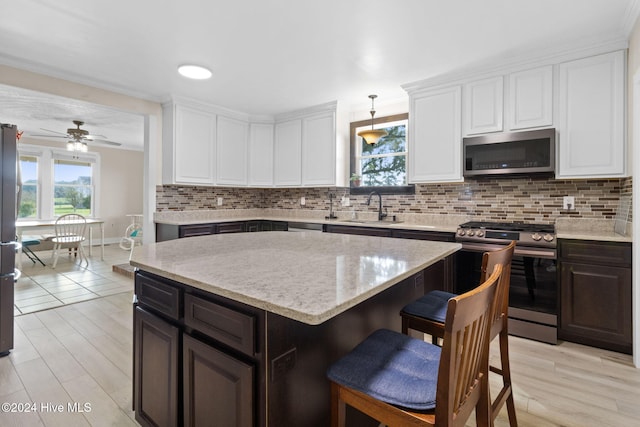 kitchen featuring stainless steel appliances, a kitchen island, ceiling fan, and light hardwood / wood-style floors