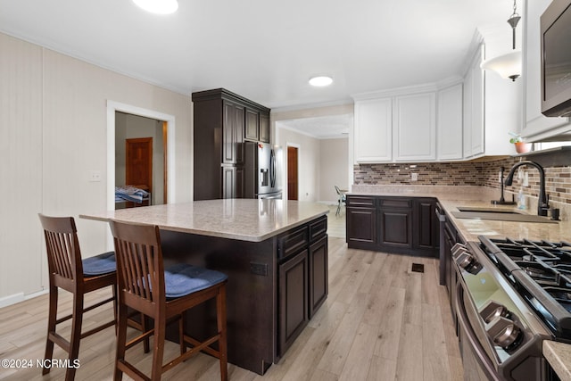 kitchen with appliances with stainless steel finishes, tasteful backsplash, sink, light hardwood / wood-style flooring, and a center island