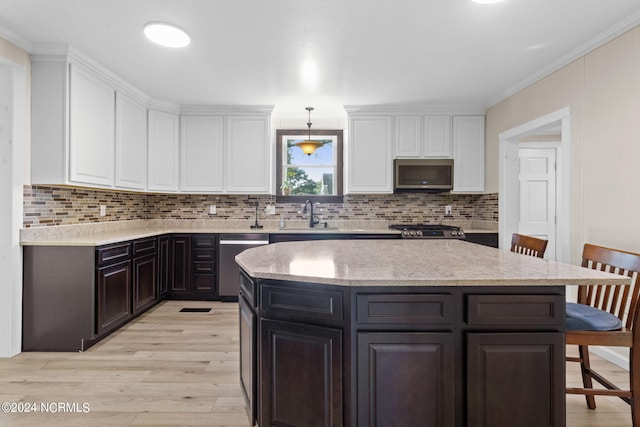 kitchen featuring white cabinetry, hanging light fixtures, light hardwood / wood-style floors, a breakfast bar, and appliances with stainless steel finishes