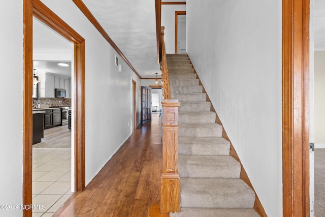 stairway with hardwood / wood-style floors and ornamental molding