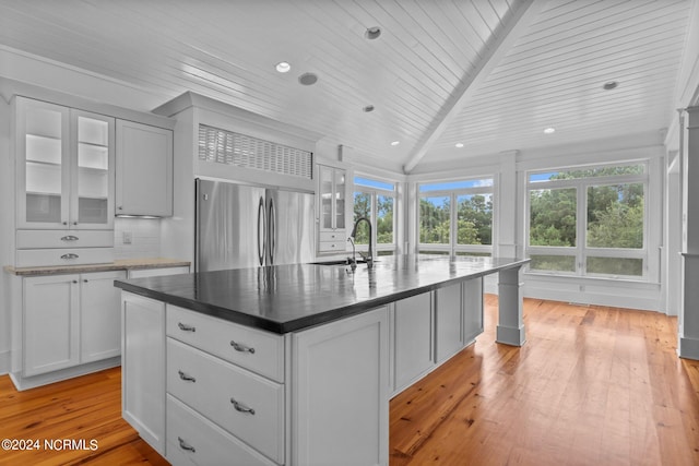 kitchen with a kitchen island with sink, light wood-type flooring, sink, decorative backsplash, and wood ceiling