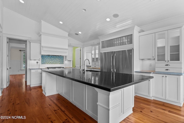 kitchen with light hardwood / wood-style floors, sink, lofted ceiling, built in refrigerator, and an island with sink