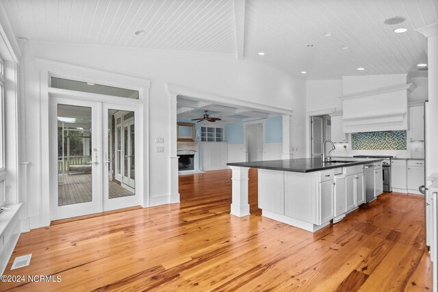 kitchen featuring light hardwood / wood-style flooring, lofted ceiling with beams, white cabinets, and tasteful backsplash