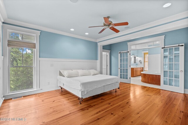 bedroom featuring ensuite bath, ornamental molding, light wood-type flooring, and ceiling fan