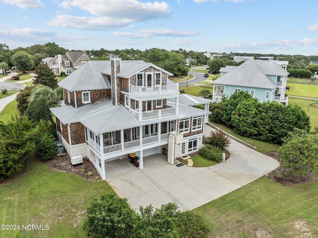 rear view of property featuring a lawn, a sunroom, and a balcony