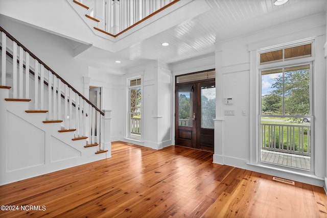 foyer with hardwood / wood-style floors, crown molding, and french doors