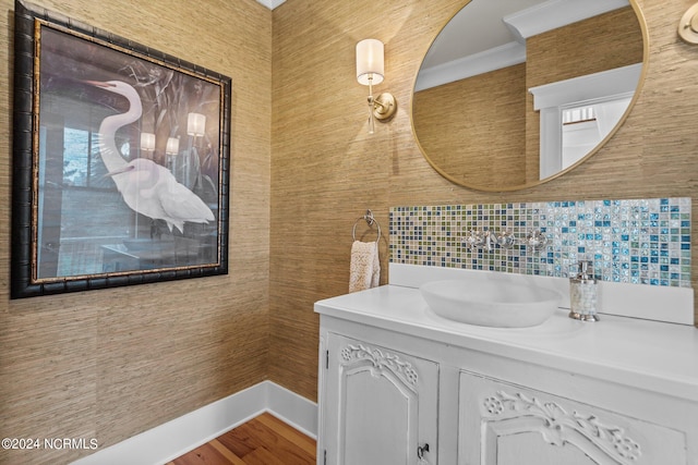 bathroom with crown molding, vanity, tasteful backsplash, and wood-type flooring