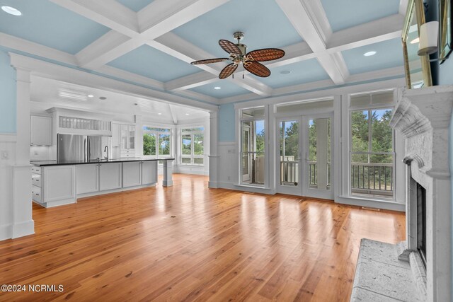 unfurnished living room featuring a healthy amount of sunlight, ceiling fan, and light hardwood / wood-style floors