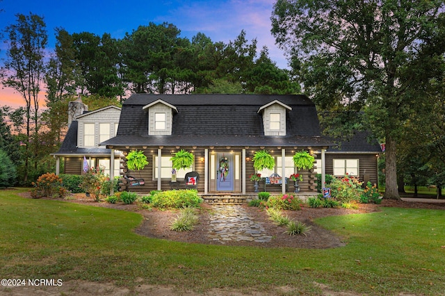 new england style home featuring a yard and covered porch