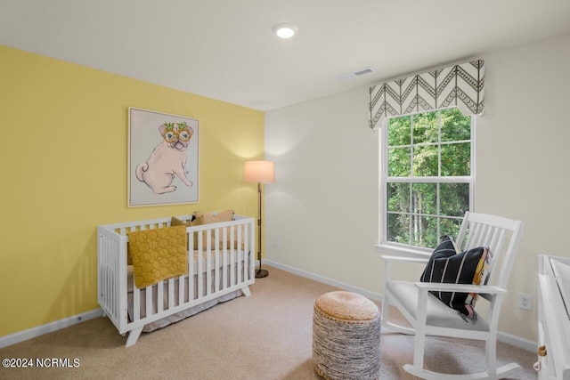 bedroom with multiple windows, carpet floors, and a crib