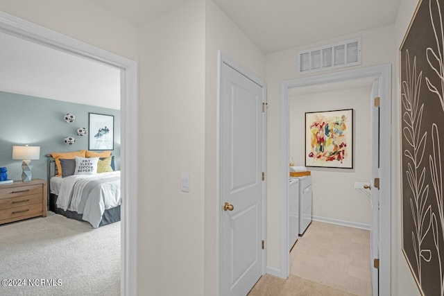 hall featuring washing machine and dryer and light colored carpet