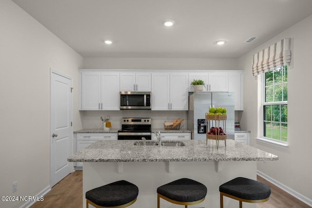 kitchen with a center island with sink, sink, appliances with stainless steel finishes, and white cabinets