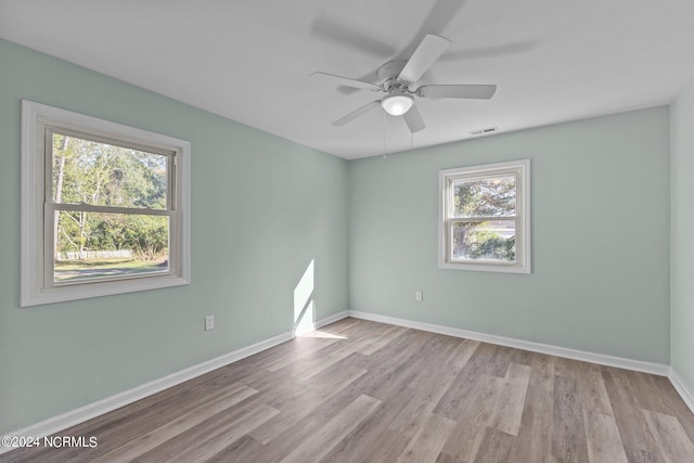 spare room featuring light hardwood / wood-style floors, ceiling fan, and a healthy amount of sunlight