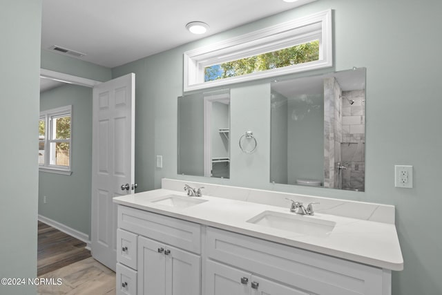 bathroom with a tile shower, vanity, toilet, and hardwood / wood-style flooring