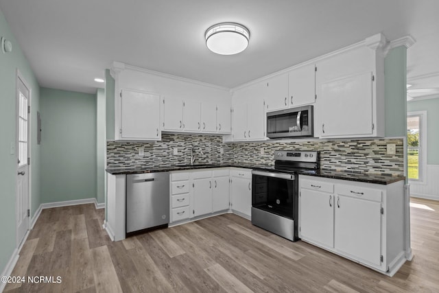 kitchen featuring light hardwood / wood-style floors, tasteful backsplash, sink, white cabinetry, and stainless steel appliances