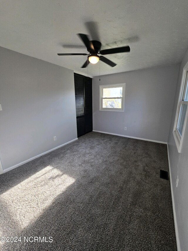 carpeted spare room featuring ceiling fan and a textured ceiling