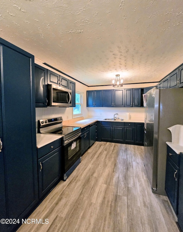 kitchen featuring a textured ceiling, sink, light hardwood / wood-style floors, a notable chandelier, and stainless steel appliances