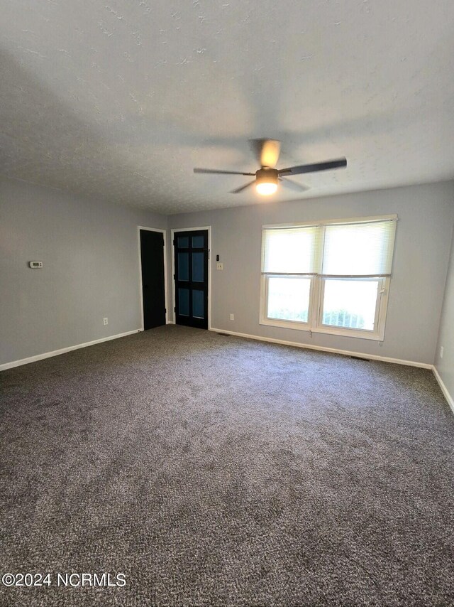 empty room featuring a textured ceiling, carpet floors, and ceiling fan