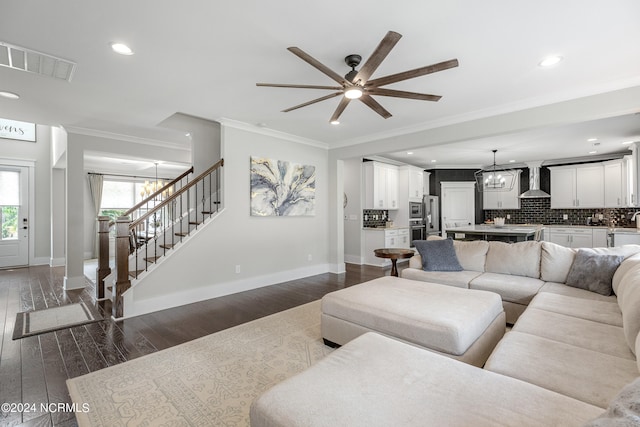 living room with ceiling fan with notable chandelier, dark hardwood / wood-style floors, and crown molding