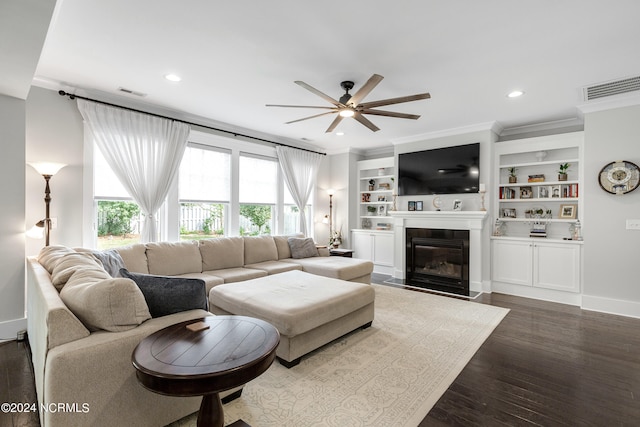 living room featuring ceiling fan, ornamental molding, dark wood-type flooring, and built in shelves