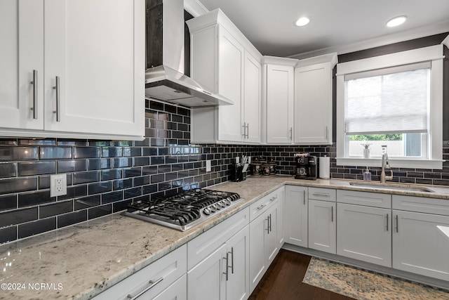 kitchen with sink, tasteful backsplash, stainless steel gas cooktop, wall chimney exhaust hood, and white cabinetry