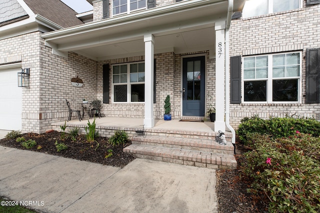 doorway to property with a garage and covered porch