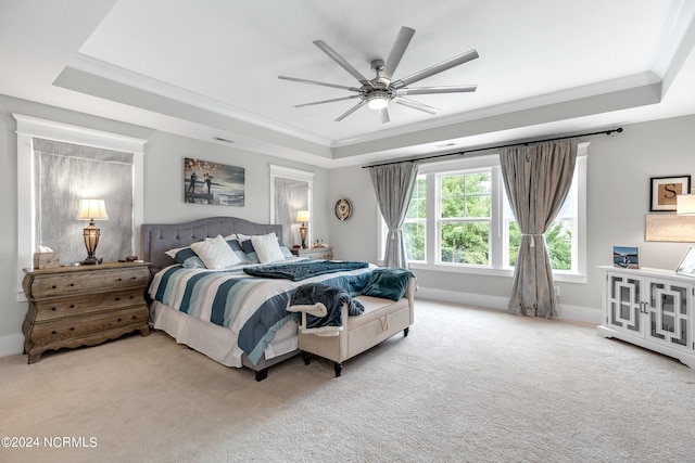 bedroom featuring ornamental molding, a tray ceiling, ceiling fan, and light colored carpet