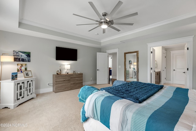 bedroom featuring connected bathroom, a tray ceiling, light carpet, and ceiling fan