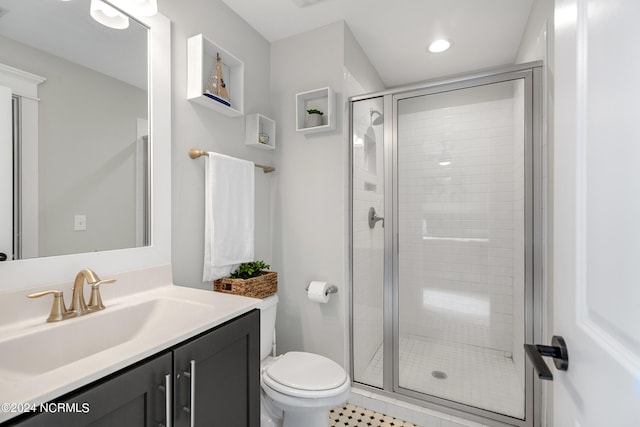 bathroom featuring a shower with shower door, vanity, and toilet