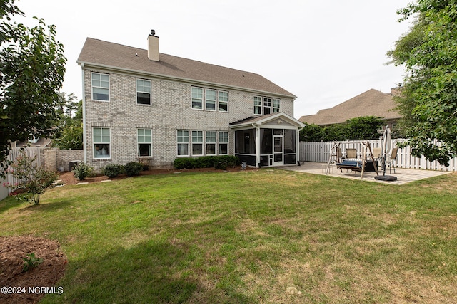 rear view of house featuring a patio, a lawn, and a sunroom