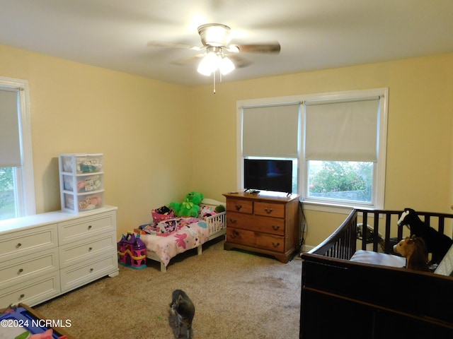 bedroom with multiple windows, light colored carpet, and ceiling fan