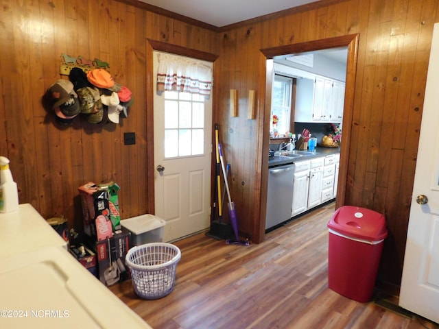 kitchen with dishwasher, hardwood / wood-style flooring, sink, wood walls, and crown molding