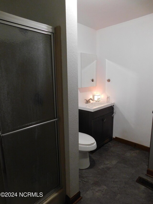 bathroom featuring an enclosed shower, vanity, and toilet