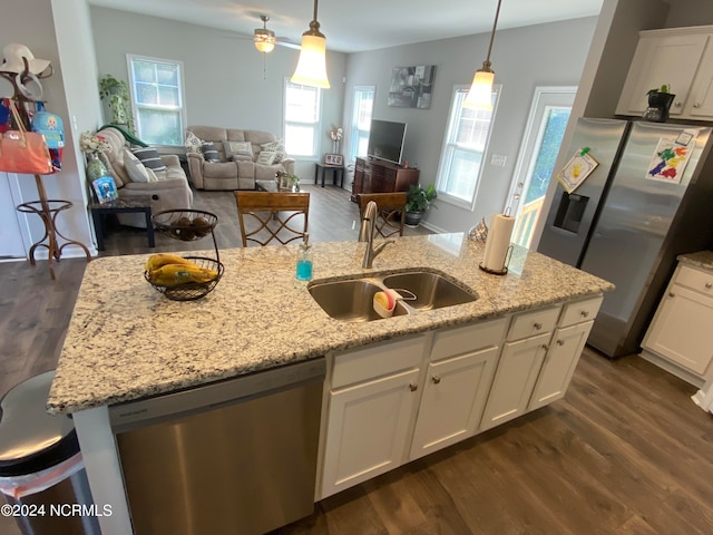 kitchen with sink, decorative light fixtures, dark wood-type flooring, appliances with stainless steel finishes, and a breakfast bar