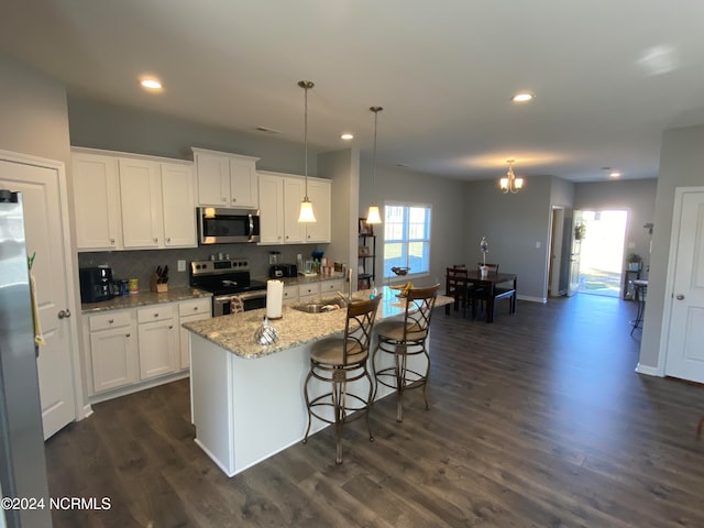 kitchen with an island with sink, white cabinets, appliances with stainless steel finishes, and pendant lighting