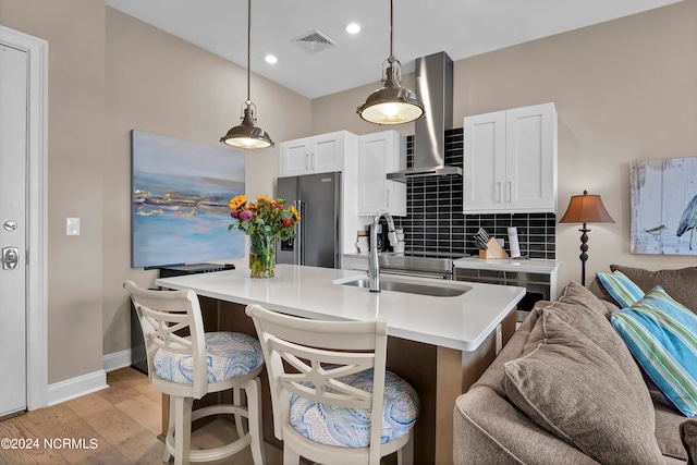 kitchen with white cabinets, a kitchen island with sink, range hood, and high end refrigerator