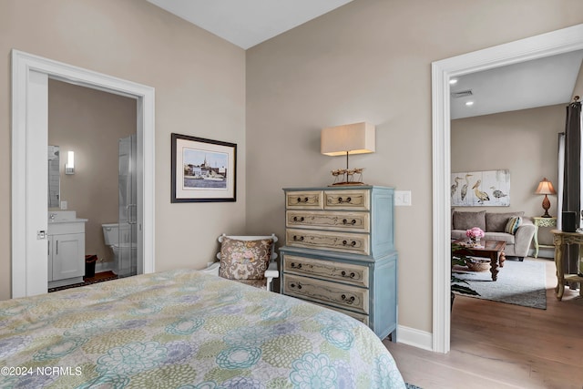 bedroom featuring ensuite bathroom and wood-type flooring