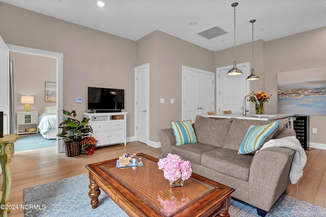 living room with light wood-type flooring, sink, and wine cooler