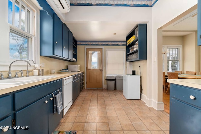 kitchen with white dishwasher, light tile patterned floors, blue cabinetry, and sink